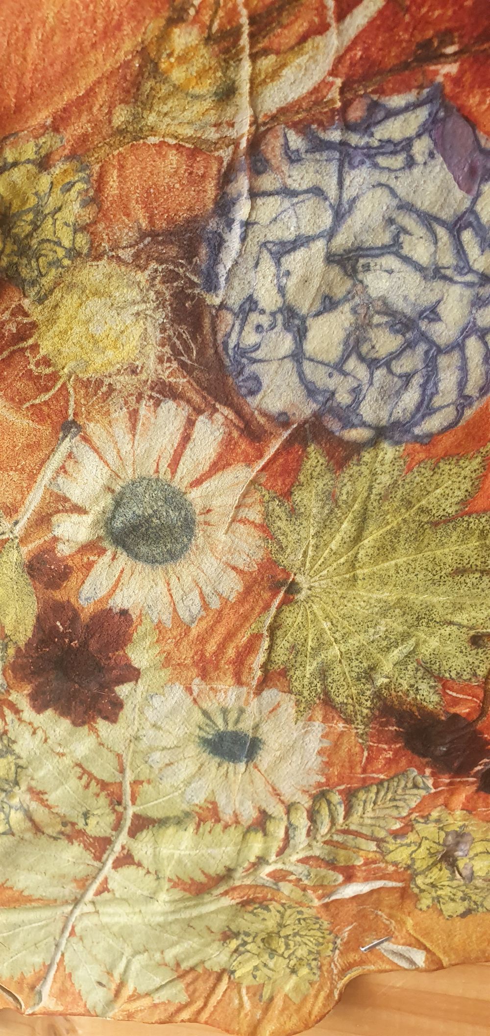Ecoprint op stof met afdrukken van zonnebloemen en bladeren in oker en roest