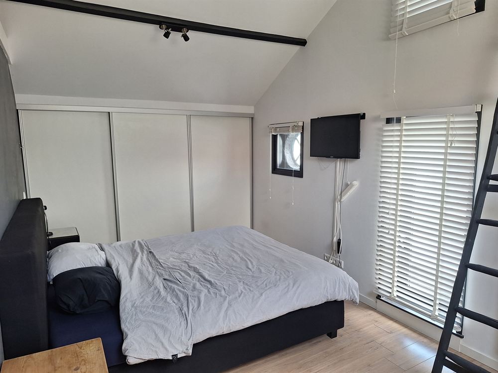 Slaapkamer onder de kap met opgemaakt tweepersoonsbed, ingebouwde kasten en een dakraam