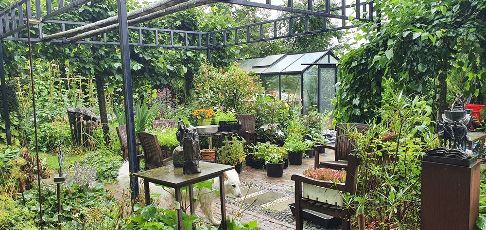 De serre met werkbanken, potten, planten en beelden
